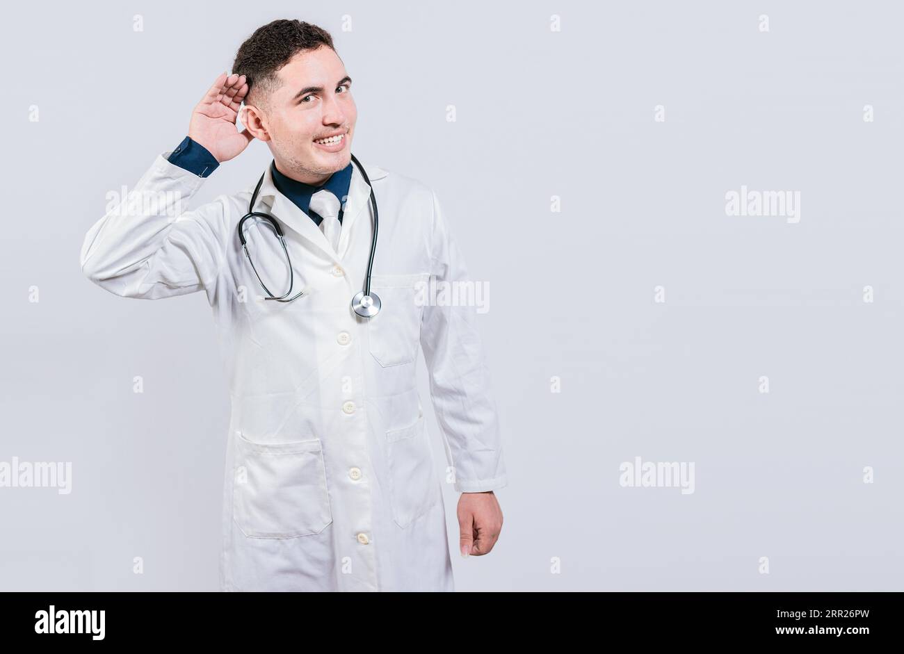 Cheerful doctor listening to a rumor. Latin doctor smiling with hand over ear isolated, Handosome doctor listening to a secret Stock Photo