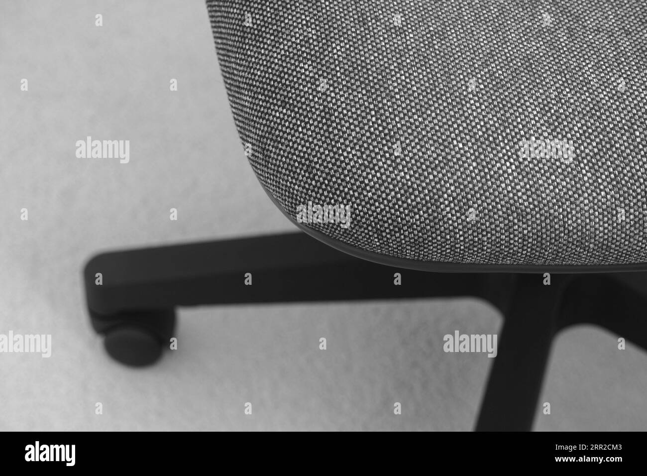 An office chair with wheels standing on a carpet. Black and white. Close up. Stock Photo