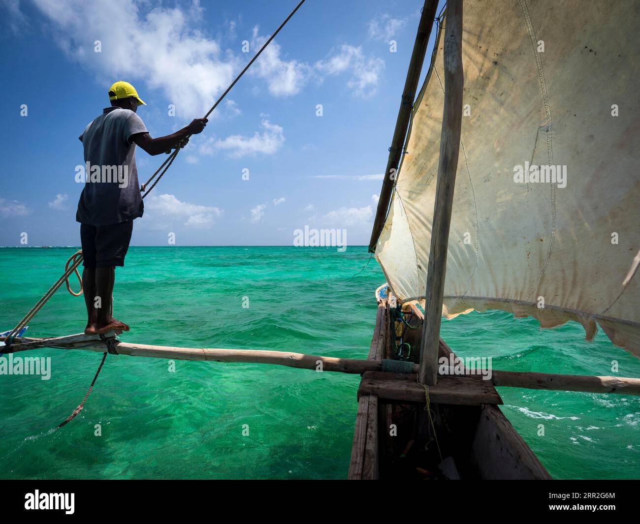 Local man steering outrigger boat, Ngalawa boat, dhow, Zanzibar, Tanzania Stock Photo