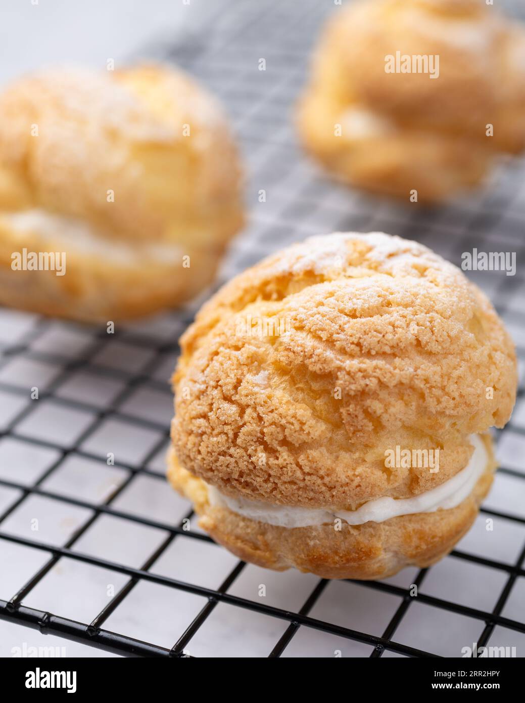 Choux cream, vanilla whipped cream stuffed cake over metal grid Stock