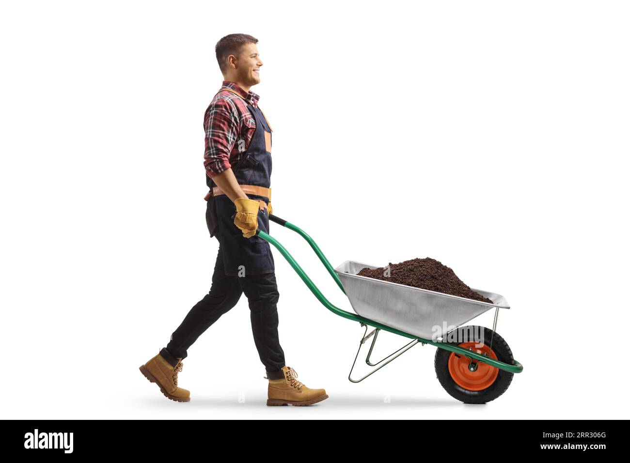 Full length profile shot of a farmer walking with a wheelbarrow full of soil isolated on white background Stock Photo