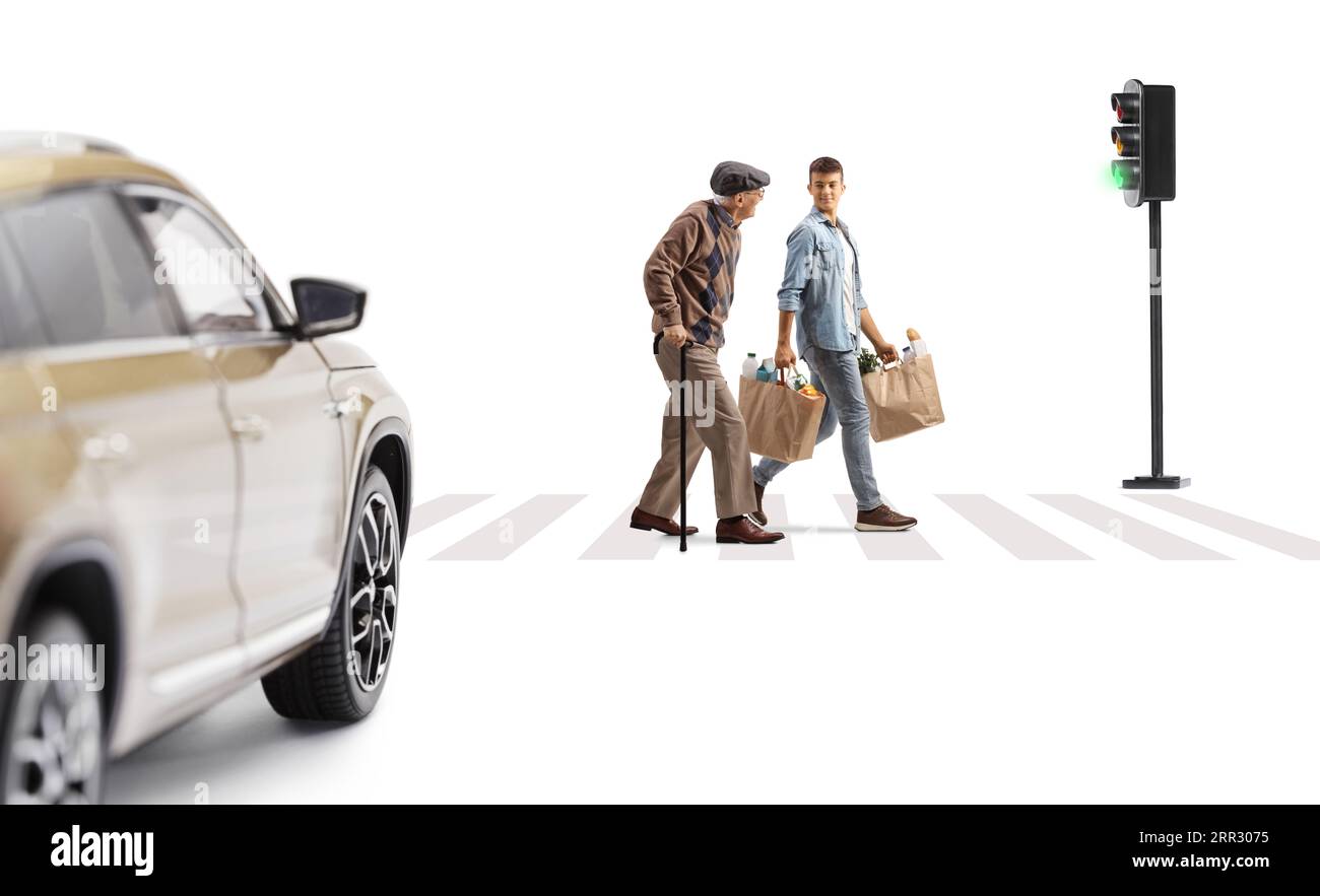 Elderly man walking with a cane and a young man carrying his grocery bags across a street isolated on white background Stock Photo