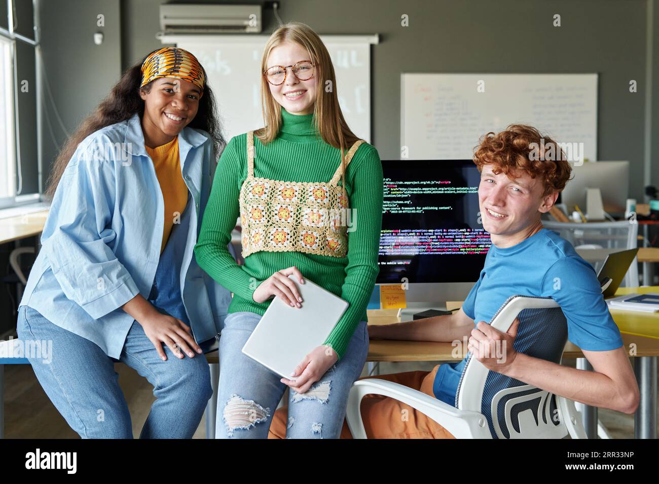 Portrait of group of students smiling at camera while studying IT at ...