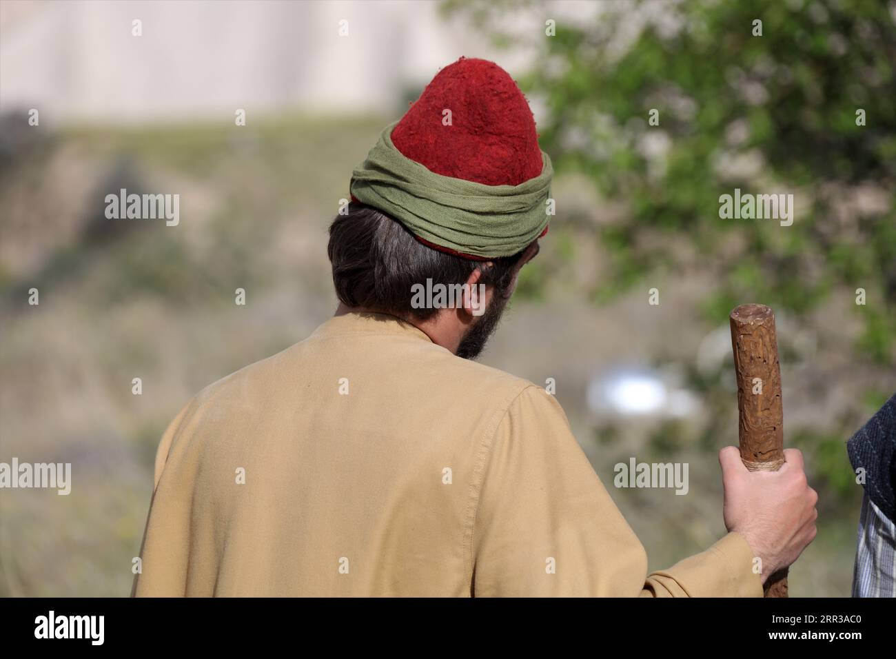 A Turkish young man in traditional clothing. Rear view of a young man walking in nature. Stock Photo