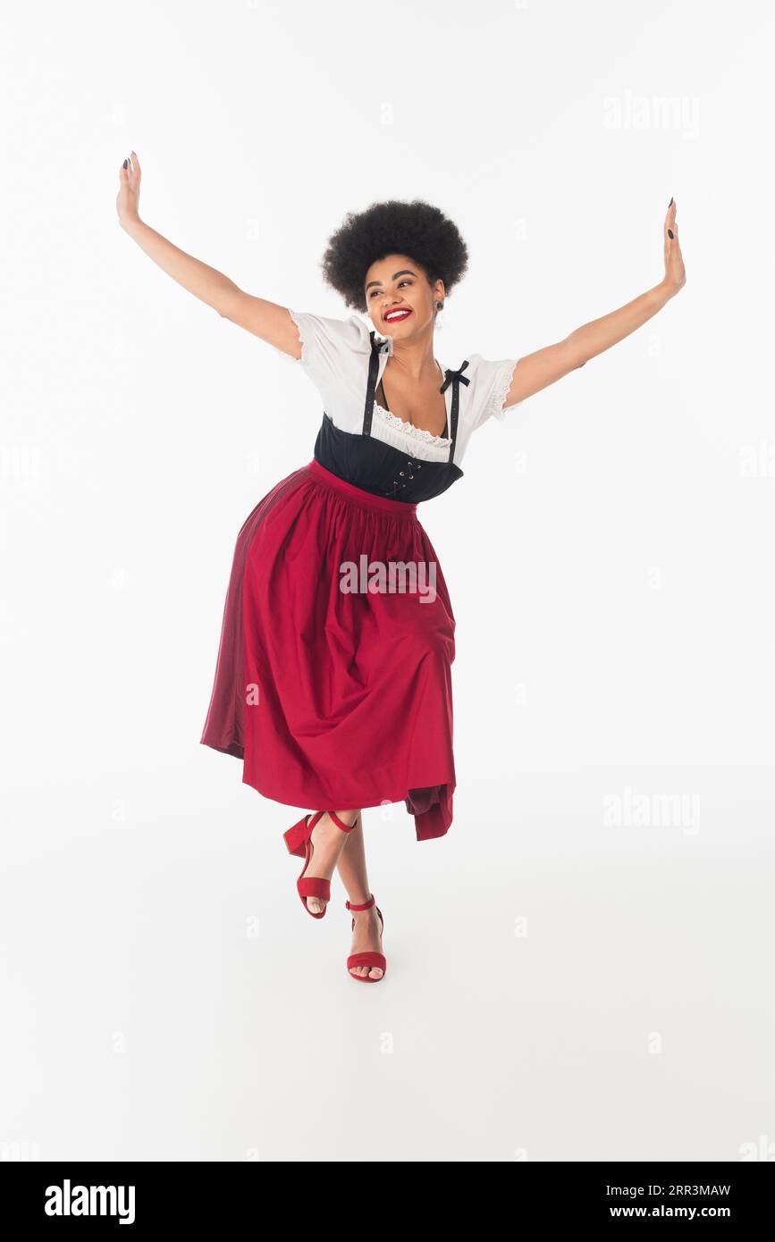 joyful african american bavarian waitress in elegant dirndl performing ...