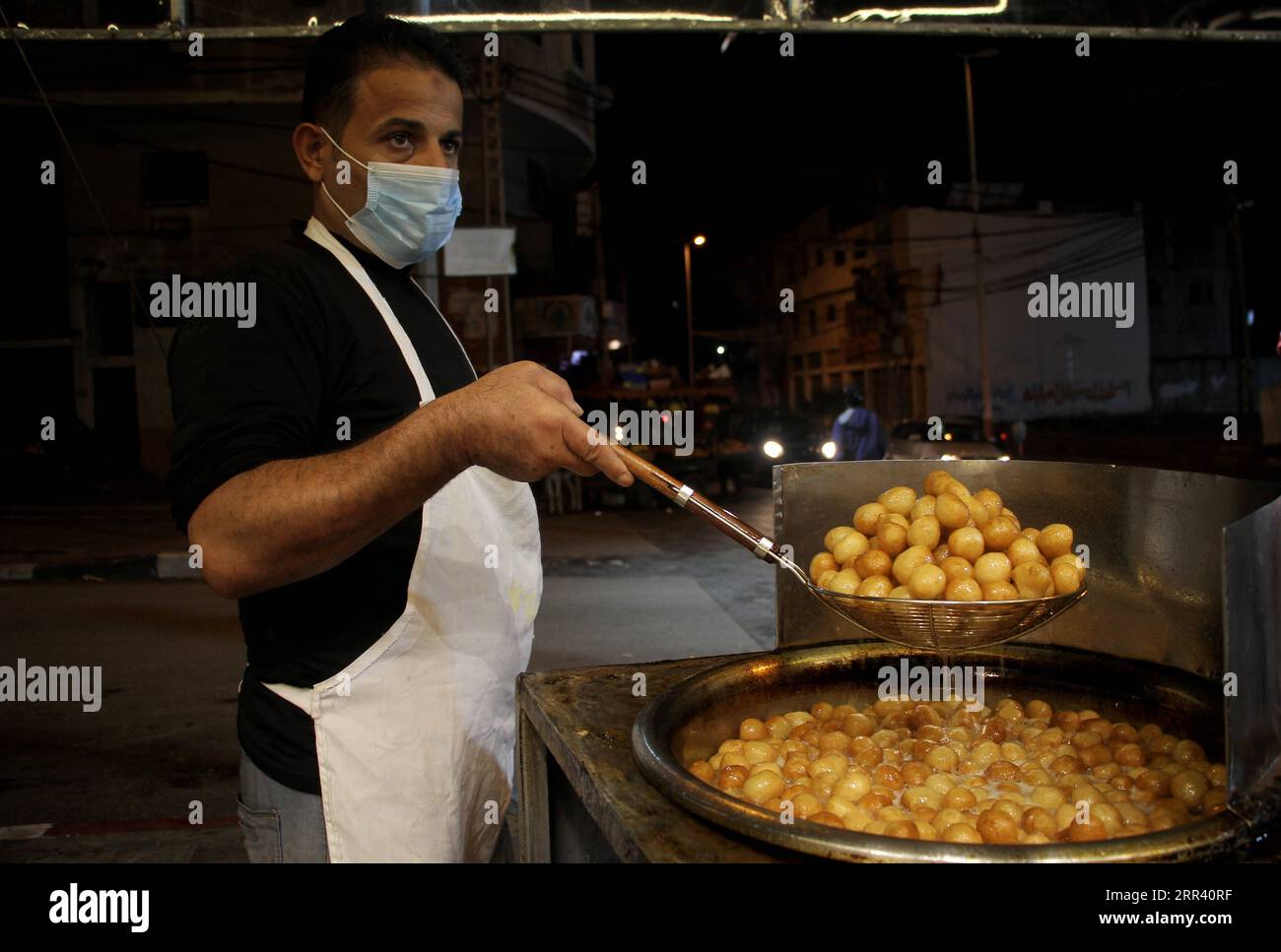 201116 -- GAZA CITY, Nov. 16, 2020 -- A Palestinian vendor makes Luqmat al Qadi sweets, a traditional pastry made of leavened and deep fried dough, soaked in syrup, in Gaza City, on Nov. 15, 2020. Photo by /Xinhua MIDEAST-GAZA CITY-SWEETS RizekxAbdeljawad PUBLICATIONxNOTxINxCHN Stock Photo