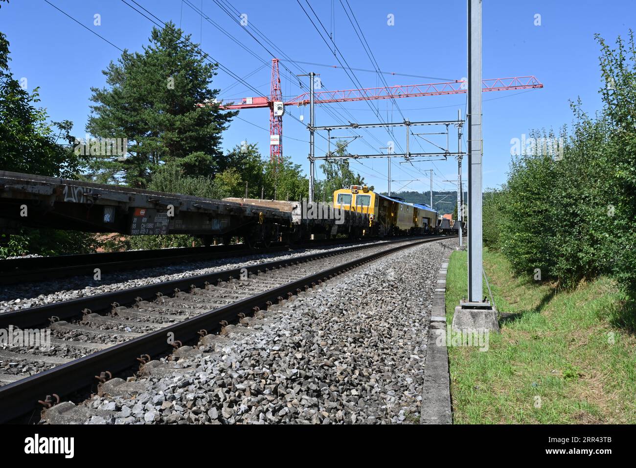 A freight train with railway carriages loaded with concrete sleepers stands on the rails leading to Urdorf station in Switzerland. Stock Photo