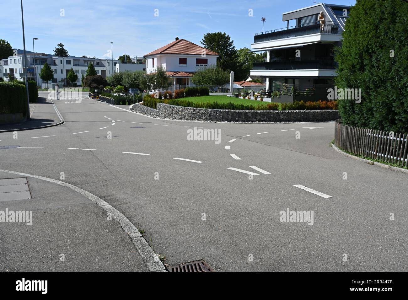 X shaped crossroad in a residential quarter of a Swiss village with broken lines helping the cars to keep on their respective side of the lane. Stock Photo