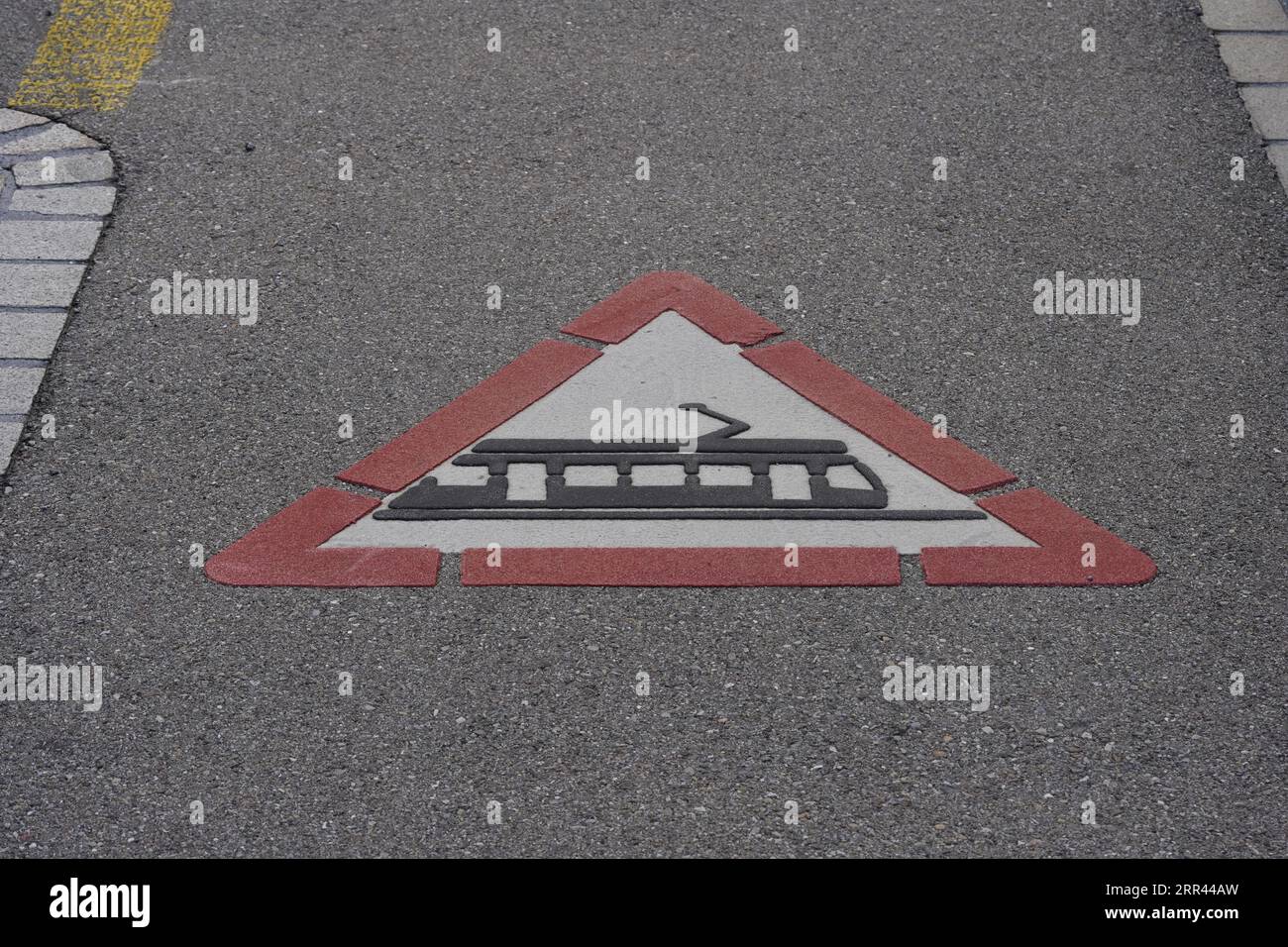 Traffic sign for tram crossing ahead painted on the ground. Stock Photo