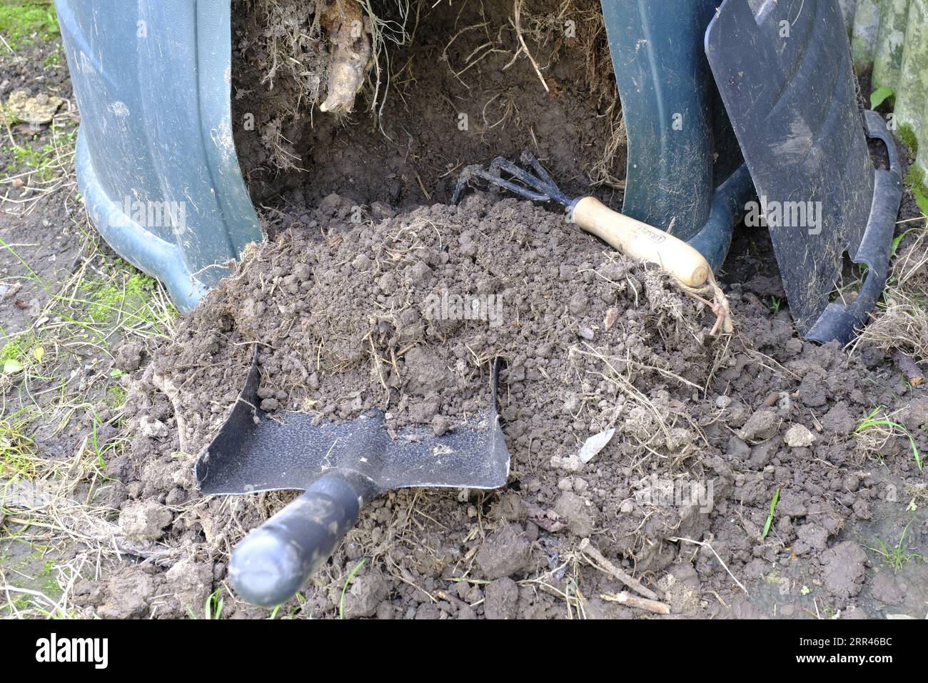 Compost bin being emptied from the bottom with the aid of a shovel and