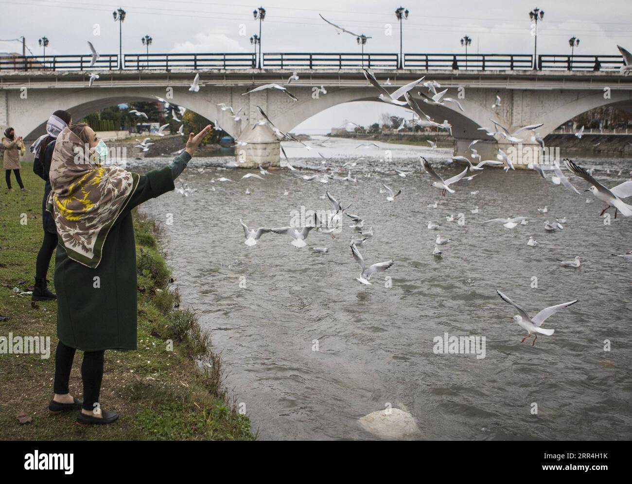 201204 -- TONEKABON, Dec. 4, 2020 -- A woman wearing a face mask feeds birds by a river in Tonekabon, northern Iran, Dec. 3, 2020. Iran s Health Ministry on Friday reported 347 new COVID-19 death cases in the past 24 hours, raising the death toll to 49,695 since the outbreak of the disease in the country on Feb. 19. Photo by /Xinhua IRAN-TONEKABON-COVID-19-CASES AhmadxHalabisaz PUBLICATIONxNOTxINxCHN Stock Photo