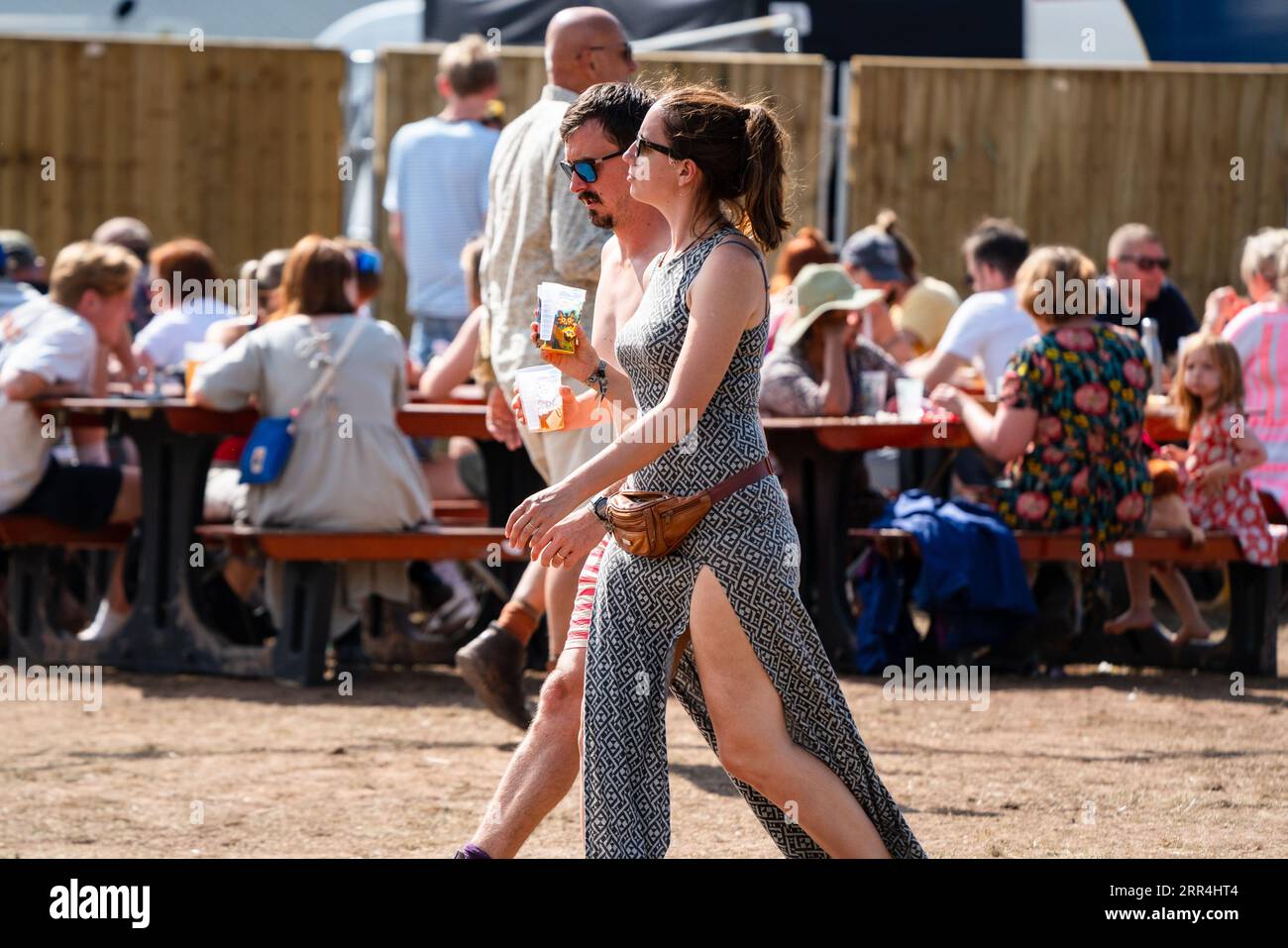 A young couple walk through the site bar area with beers at Green Man