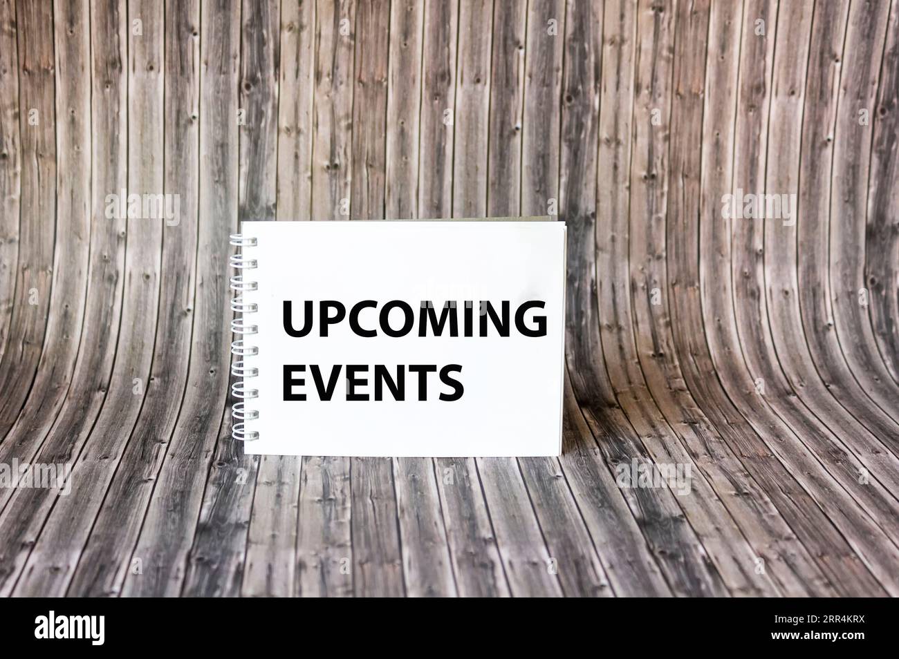 Upcoming events text on notepad and wooden background. Stock Photo