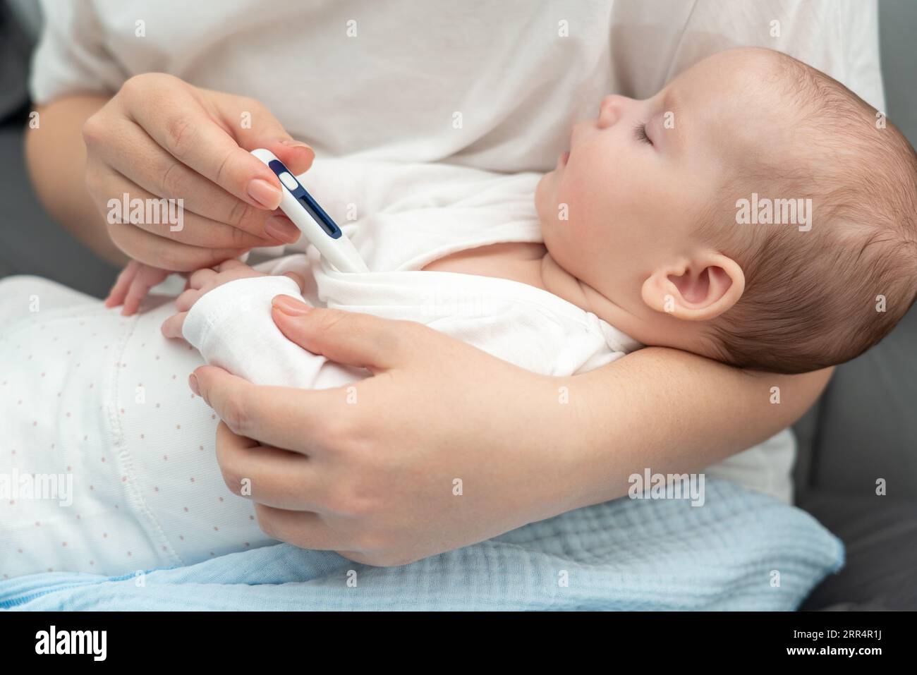 Slumbering infant undergoes temperature check, Concept of vigilant maternal care Stock Photo