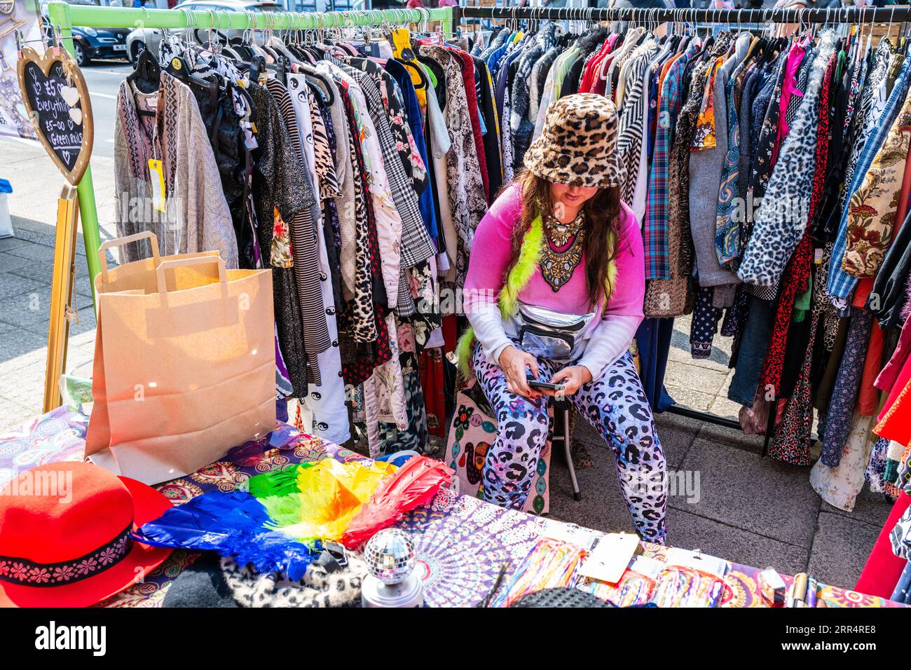 Vintage clothes stall at Bridport Saturday street market on a sunny summer morning. Colourful, quirky, trader, clothes rack. Money. Stock Photo