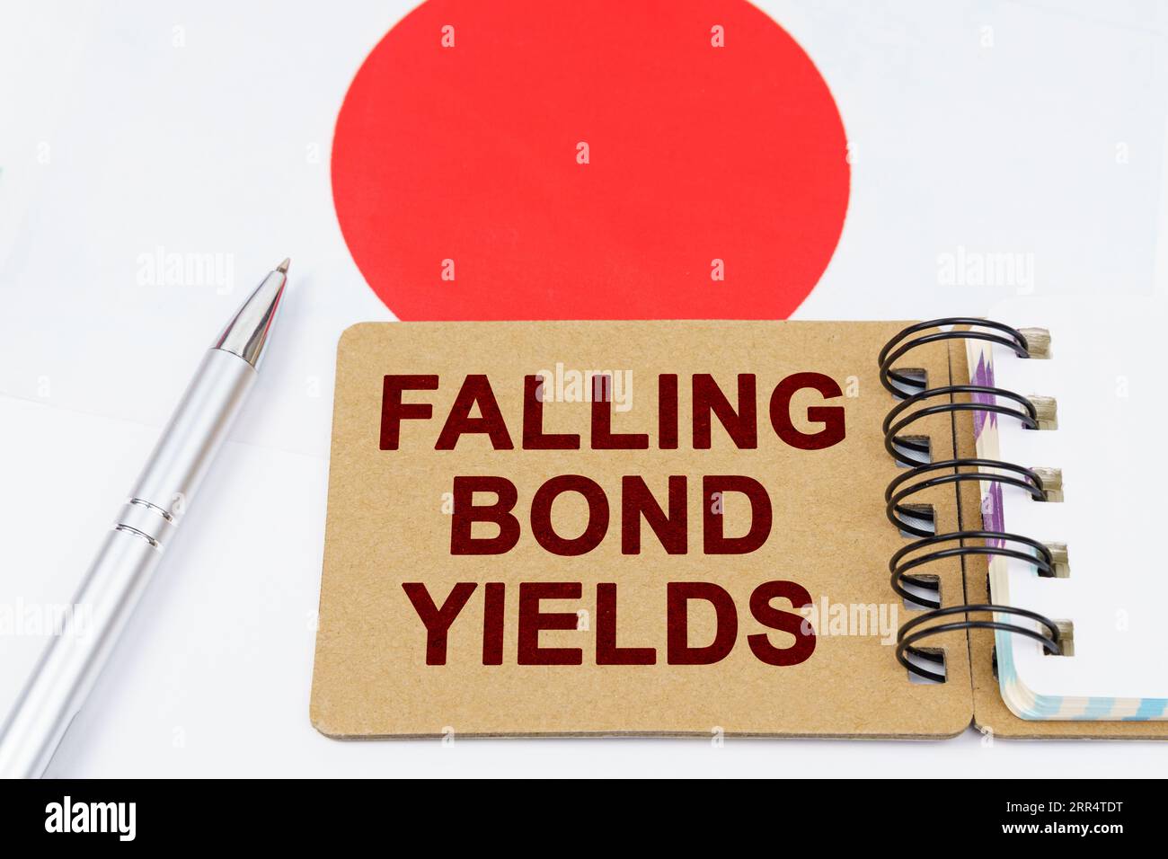 Economy and finance concept. On the flag of Japan lies a pen and a notebook with the inscription - falling bond yields Stock Photo