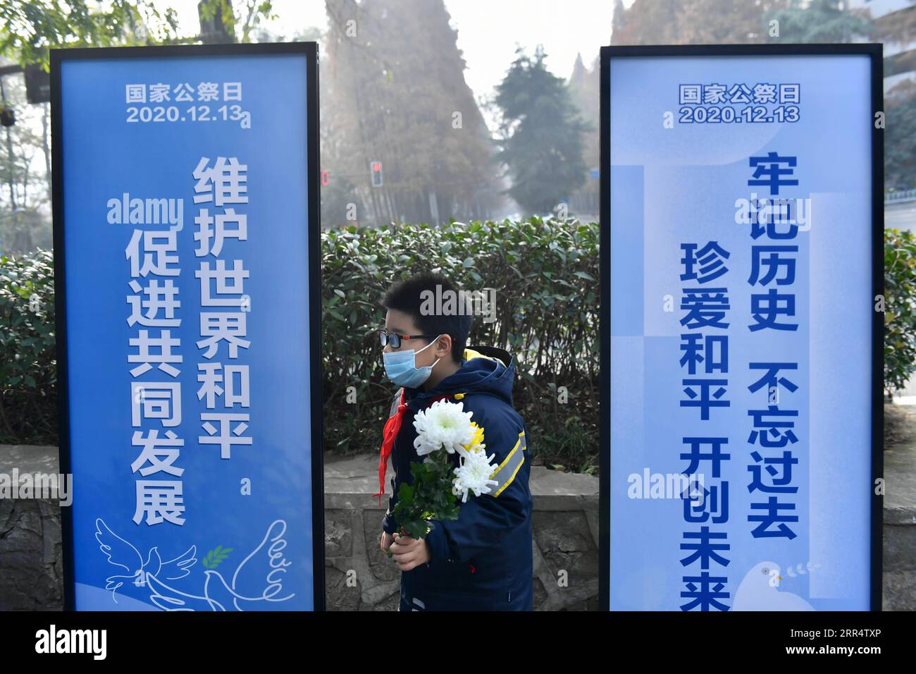 201213 -- NANJING, Dec. 13, 2020  -- A pupil holds a bunch of flowers during an activity in commemoration of victims of the Nanjing Massacre at a mass burial place on the occasion of the seventh national memorial day in Nanjing, capital of east China s Jiangsu Province, Dec. 13, 2020.  CHINA-NANJING MASSACRE-COMMEMORATION CN Xinhua PUBLICATIONxNOTxINxCHN Stock Photo