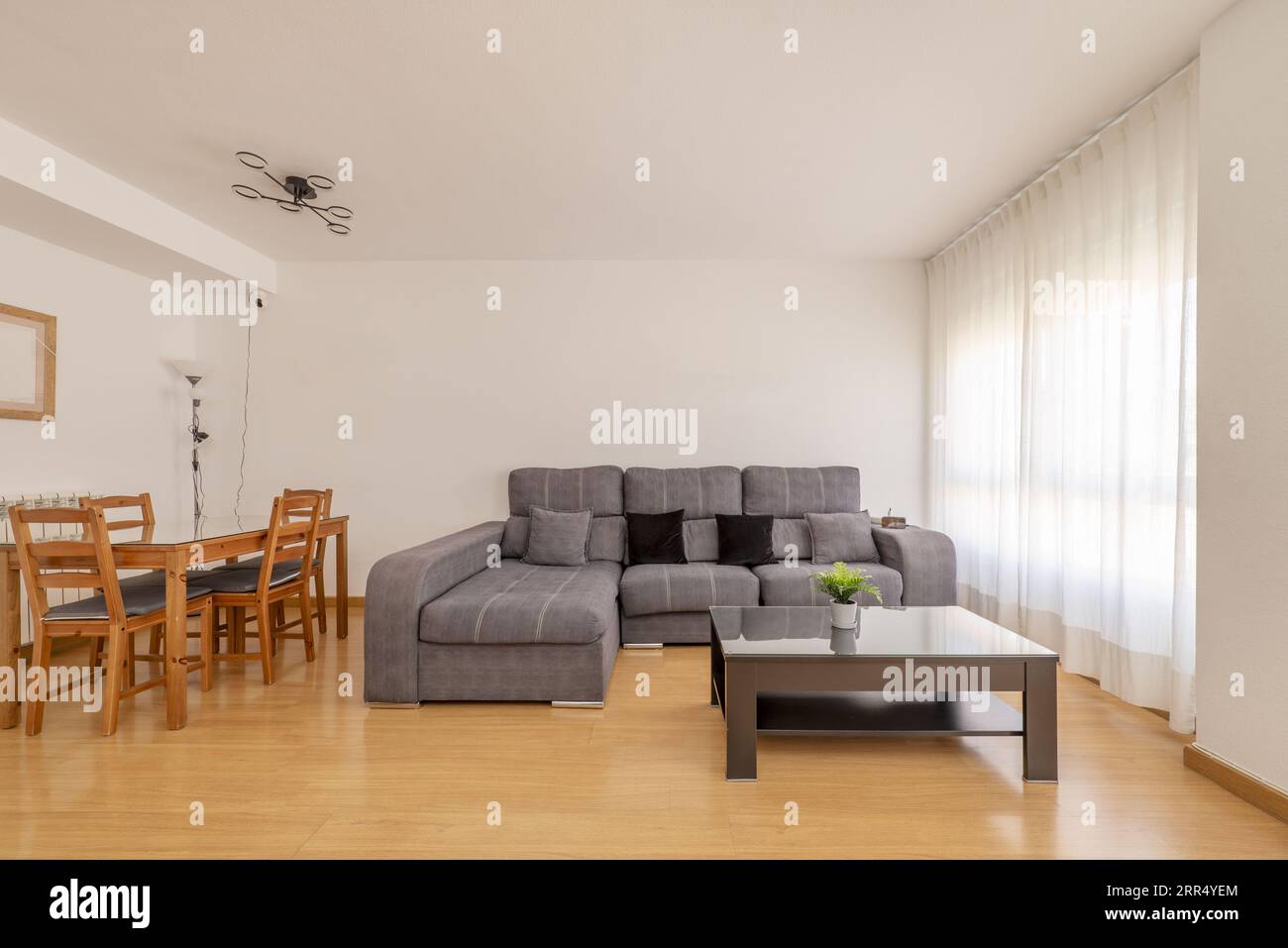 A living room with some wooden furniture, white walls, wooden floors