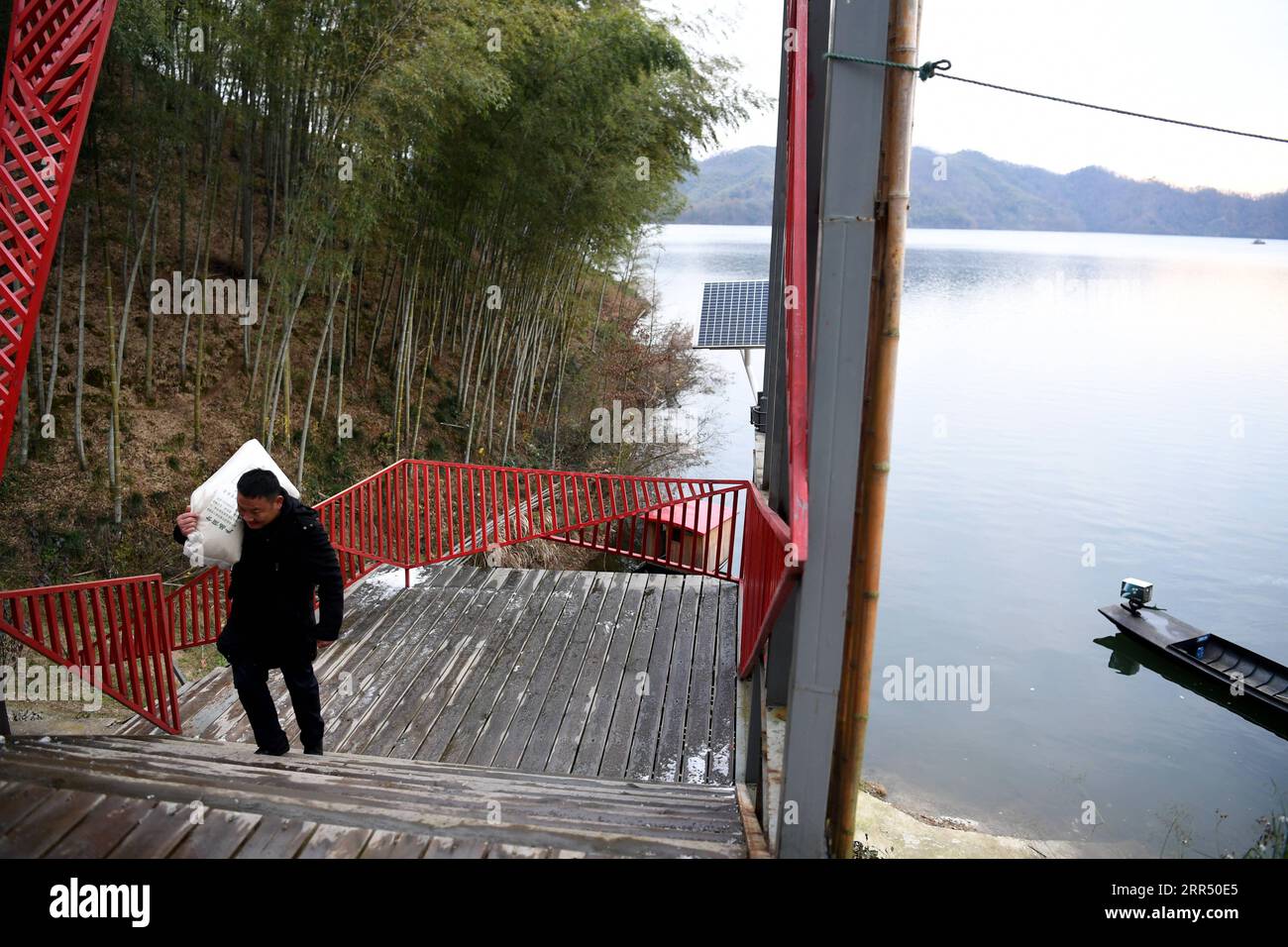 201218 -- JINZHAI, Dec. 18, 2020 -- Yu Jiajun carries a bag of rice from the boat to the health station in Jinzhai County of Luan City, east China s Anhui Province, Dec. 15, 2020. Deep in the Xianghongdian Reservoir area in Jinzhai County of Luan City, east China s Anhui Province, there is an isolated island, which used to be home to over 40 poor families. Yu Jiajun, 42, is the only doctor in the village. In the past, there was no health station on the island. Villagers had to row a boat for two or three hours to go to the health center in Mabu Township to see the doctor. Yu said. When Yu Jiaj Stock Photo