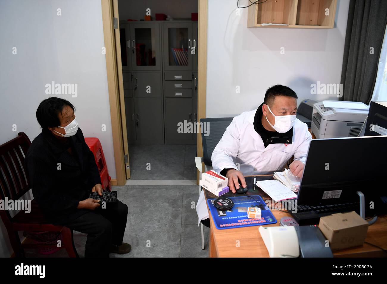 201218 -- JINZHAI, Dec. 18, 2020 -- Yu Jiajun treats a villager at the new health station in Jinzhai County of Luan City, east China s Anhui Province, Dec. 15, 2020. Deep in the Xianghongdian Reservoir area in Jinzhai County of Luan City, east China s Anhui Province, there is an isolated island, which used to be home to over 40 poor families. Yu Jiajun, 42, is the only doctor in the village. In the past, there was no health station on the island. Villagers had to row a boat for two or three hours to go to the health center in Mabu Township to see the doctor. Yu said. When Yu Jiajun returned to Stock Photo