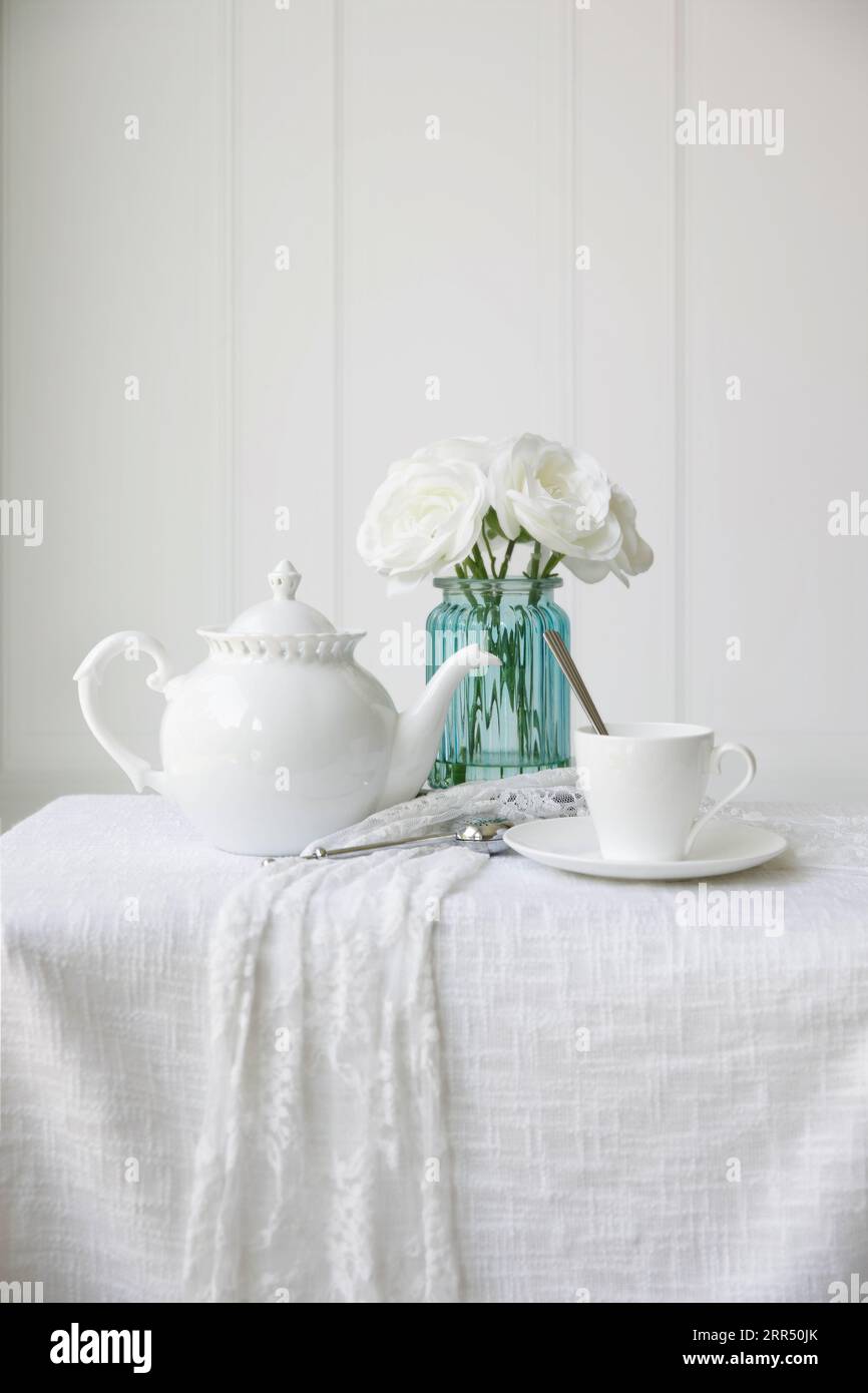 A still life with white teapot and roses. Stock Photo