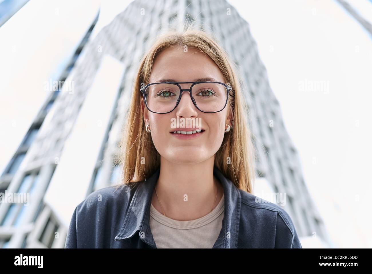 Teenage female in glasses looking at camera, glass skyscrapers ...