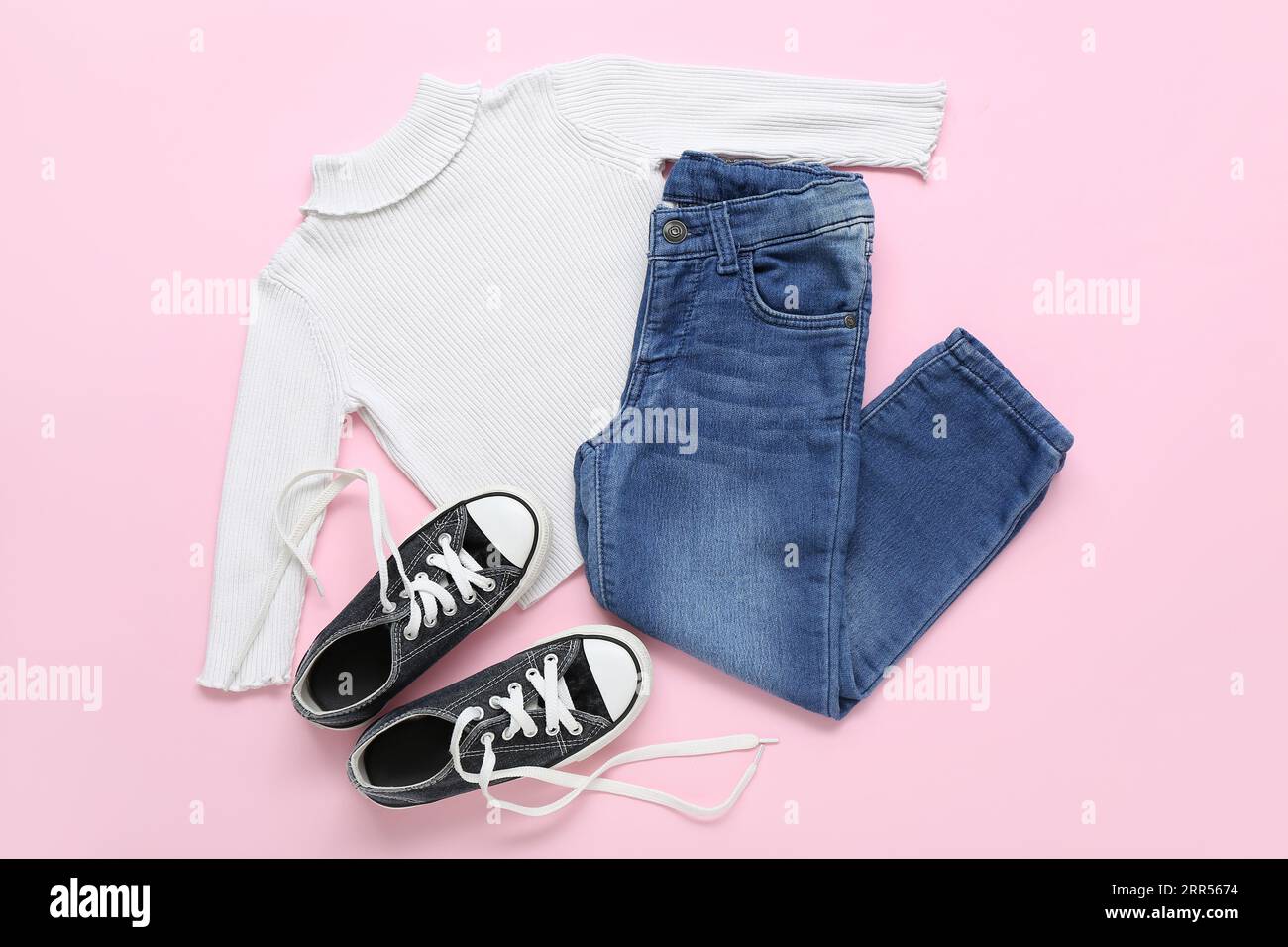 Stylish children's sweater, jeans and shoes on pink background Stock