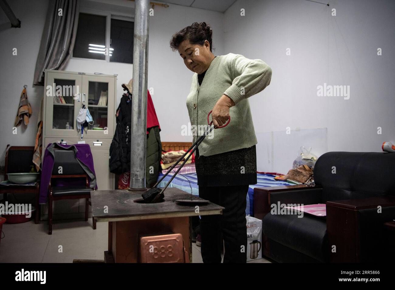 201225 -- YINCHUAN, Dec. 25, 2020 -- Ding Haiyan adds some coal to the stove in her office where she lives and works in Hejiayuan Village of Xihaigu in northwest China s Ningxia Hui Autonomous Region, Oct. 28, 2020. Xihaigu, a largely mountainous region in northwest Ningxia, was once inflicted by deep poverty and labeled the most unfit place for human settlement by the United Nations in the 1970s due to land reclamation, drought, and a fragile ecological environment. On Nov. 16, 2020, Xihaigu historically bid farewell to absolute poverty, during which she power played an indispensable role. Di Stock Photo