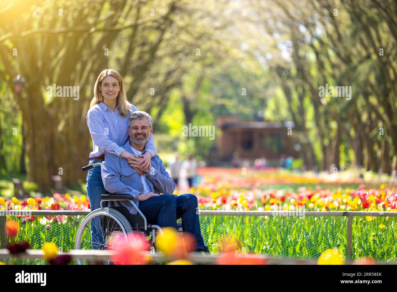 Man in wheelchair with loving woman in park Stock Photo - Alamy