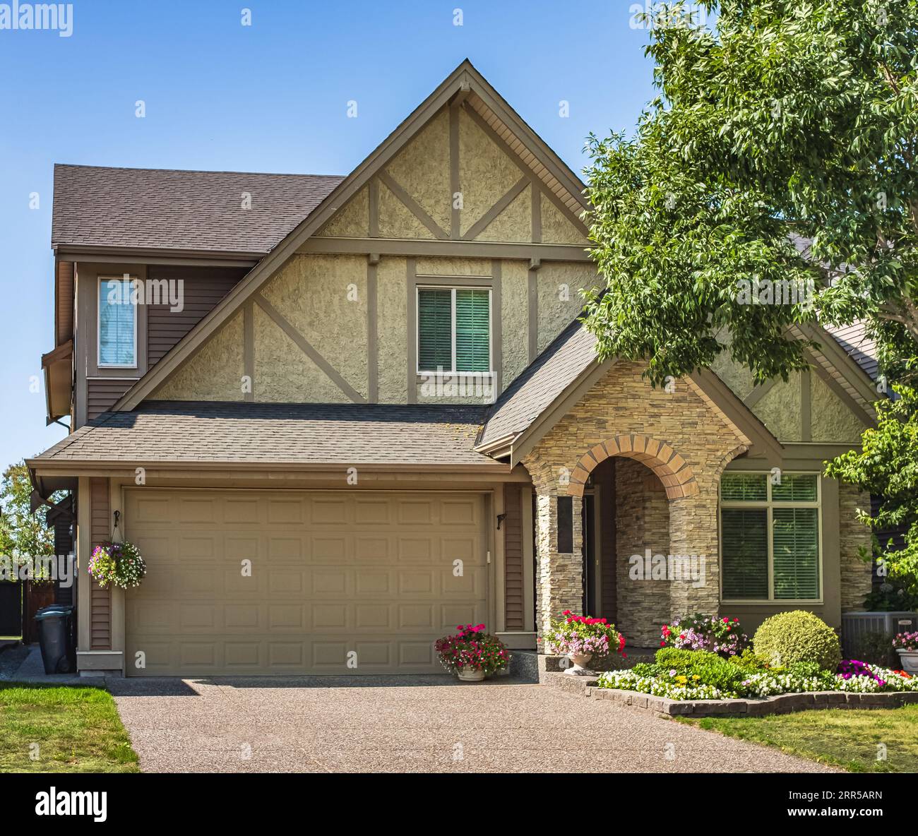 Elegant detached house and garage. Big family house with garage car parked in front. Residential house with concrete driveway and entrance door. Custo Stock Photo