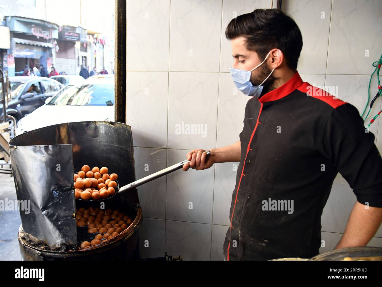 210108 -- DAMASCUS, Jan. 8, 2021 -- A sweet maker makes Luqmat al-Qadi sweets, a traditional pastry made of leavened and deep fried dough, in Damascus, Syria, Jan. 7, 2021. Photo by /Xinhua SYRIA-DAMASCUS-SWEET AmmarxSafarjalani PUBLICATIONxNOTxINxCHN Stock Photo