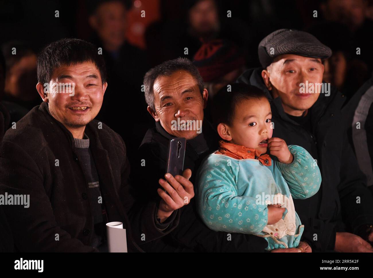 210109 -- WUSHAN, Jan. 9, 2021 -- Mao Xianglin 2nd, L and villagers watch a performance organized by the cultural center of Wushan County at Xiazhuang Village, Zhuxian Township, Wushan County of southwest China s Chongqing, Jan. 6, 2021. For those who lived in Xiazhuang Village, it once took them two days to reach the nearest county. Thanks to the unceasing efforts of Mao Xianglin, the onerous travelling has become a history. In 1997, 38-year-old Mao Xianglin, the secretary of Communist Party of China CPC branch of Xiazhuang Village and head of the village committee, mobilized the villagers to Stock Photo