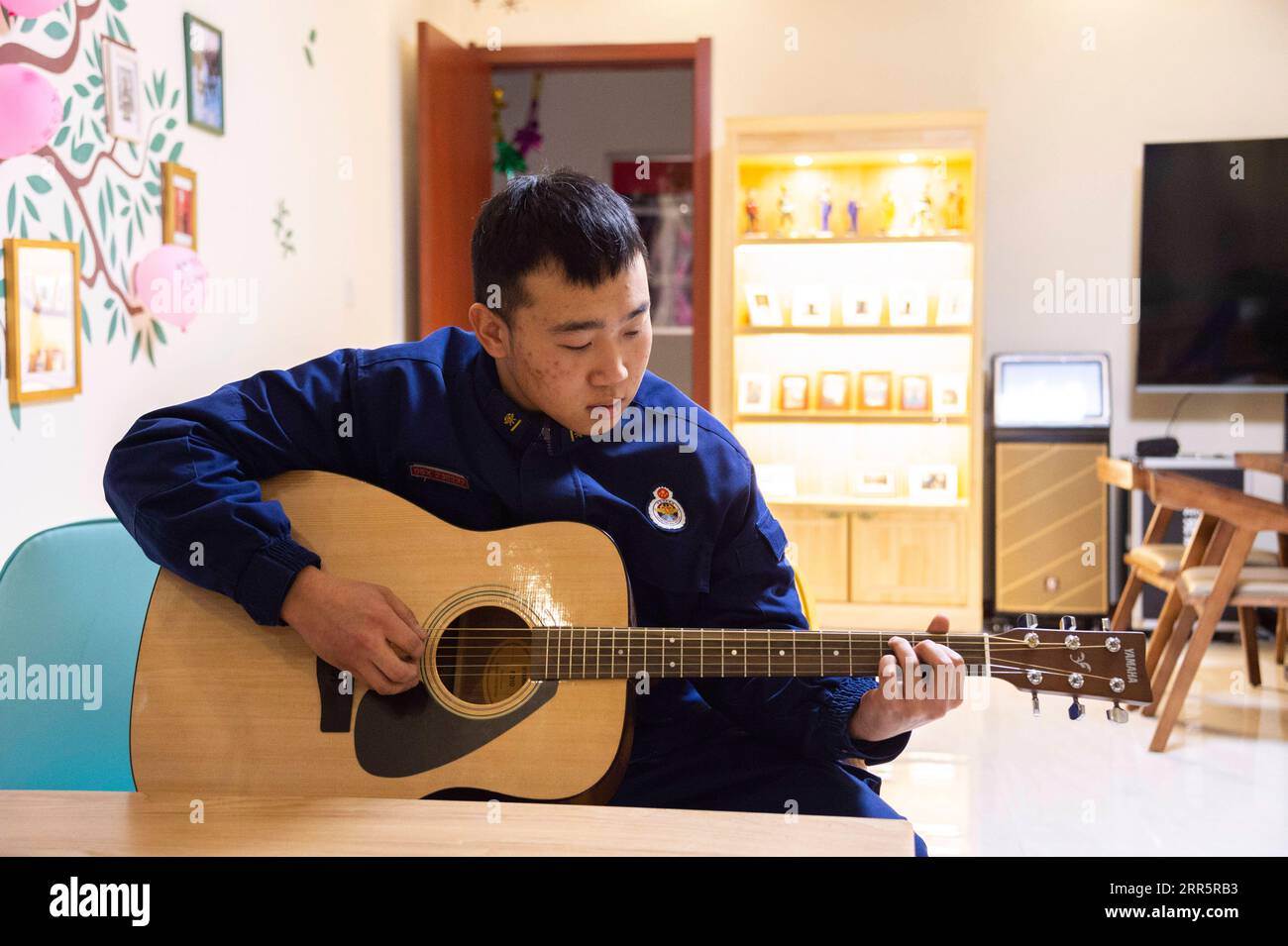 210114 -- MOHE, Jan. 14, 2021 -- Firefighter Wu Junming plays the guitar in the activity room of the fire station in Beiji Village of Mohe City, northeast China s Heilongjiang Province, Jan. 13, 2021. Firefighters stick to their post and keep training despite the freezing weather in Mohe, the northernmost city in China, where the temperature is often below minus 40 degrees Celsius in winter.  CHINA-HEILONGJIANG-MOHE-WINTER-FIRE FIGHTERSCN XiexJianfei PUBLICATIONxNOTxINxCHN Stock Photo