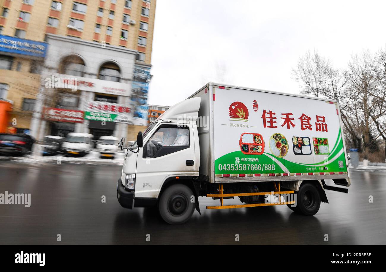 210203 -- TONGHUA, Feb. 3, 2021 -- A distribution truck loaded with boxed meals drives on the street in Tonghua City of northeast China s Jilin Province, Jan. 21, 2021. The city is slowing down to curb the pandemic, but we re not closing up. Instead, we re busier than ever, said Zhao Hongxia, general manager of Jiahe Catering Company. The company was originally a boxed meal supplier for primary and secondary schools in Tonghua City. Since the COVID-19 outbreak in Tonghua, the company has accepted a new task of providing meals to front-line staff and people under quarantine. More than 30,000 bo Stock Photo