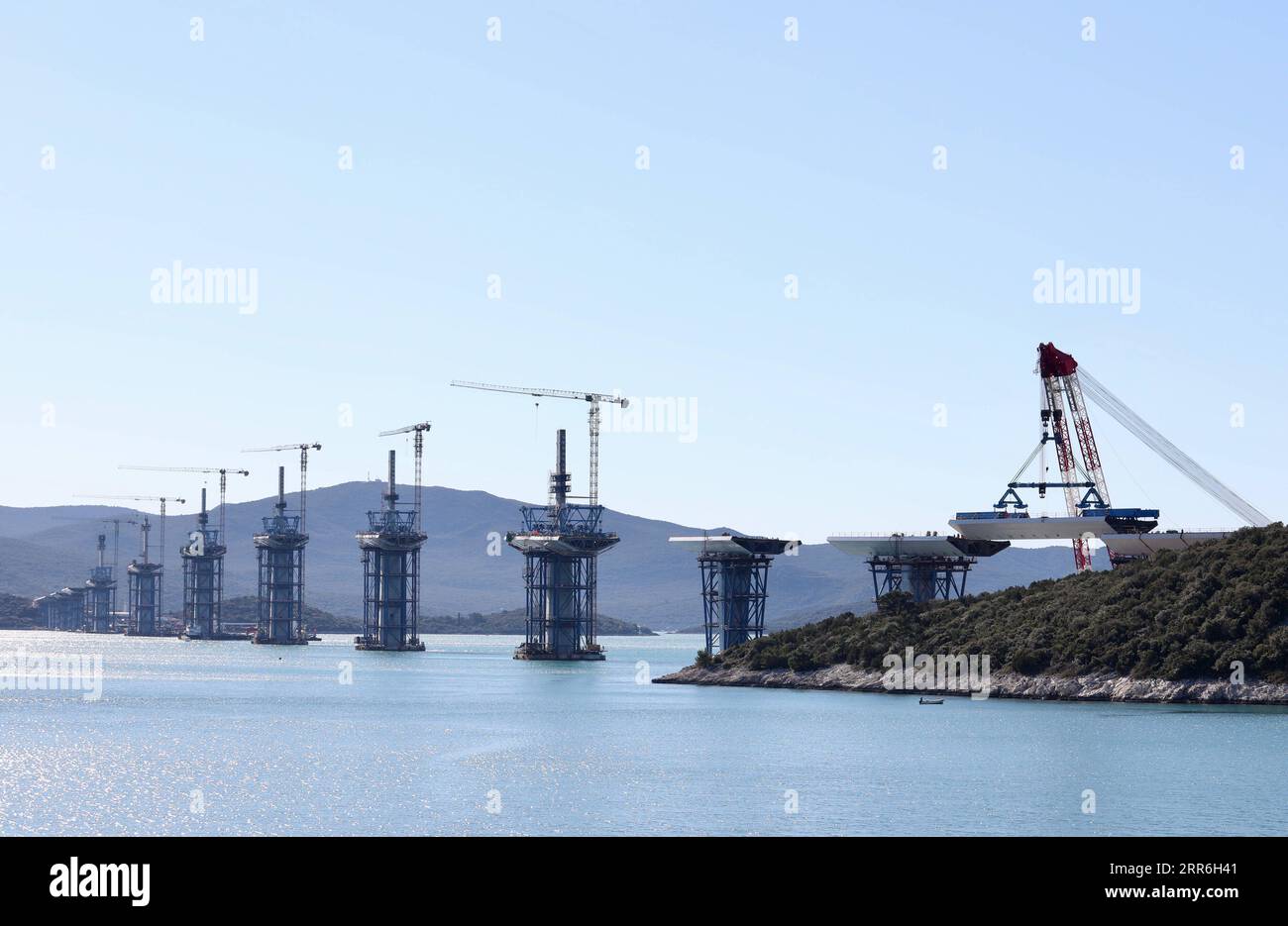 210215 -- KOMARNA CROATIA, Feb. 15, 2021 -- A crane carries a steel box girder to connect the Croatian mainland with the first sea-based pillar of the Peljesac Bridge near Komarna, Croatia, Feb. 15, 2021. The construction of the Peljesac Bridge, the biggest infrastructure project in Croatia, will be completed in June 2022, Prime Minister Andrej Plenkovic announced on Monday after visiting the site. The 2.4-kilometer-long Peljesac Bridge connects Croatia s southernmost Dubrovnik-Neretva County to the rest of the mainland, giving the southeastern European country a continuous land link that bypa Stock Photo