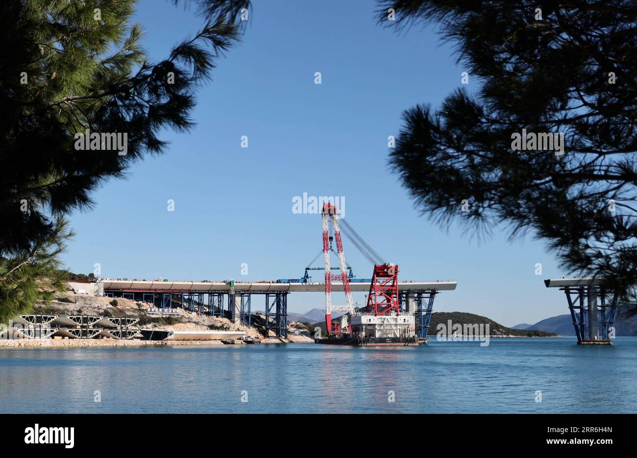 210215 -- KOMARNA CROATIA, Feb. 15, 2021 -- A crane carries a steel box girder to connect the Croatian mainland with the first sea-based pillar of the Peljesac Bridge near Komarna, Croatia, Feb. 15, 2021. The construction of the Peljesac Bridge, the biggest infrastructure project in Croatia, will be completed in June 2022, Prime Minister Andrej Plenkovic announced on Monday after visiting the site. The 2.4-kilometer-long Peljesac Bridge connects Croatia s southernmost Dubrovnik-Neretva County to the rest of the mainland, giving the southeastern European country a continuous land link that bypa Stock Photo