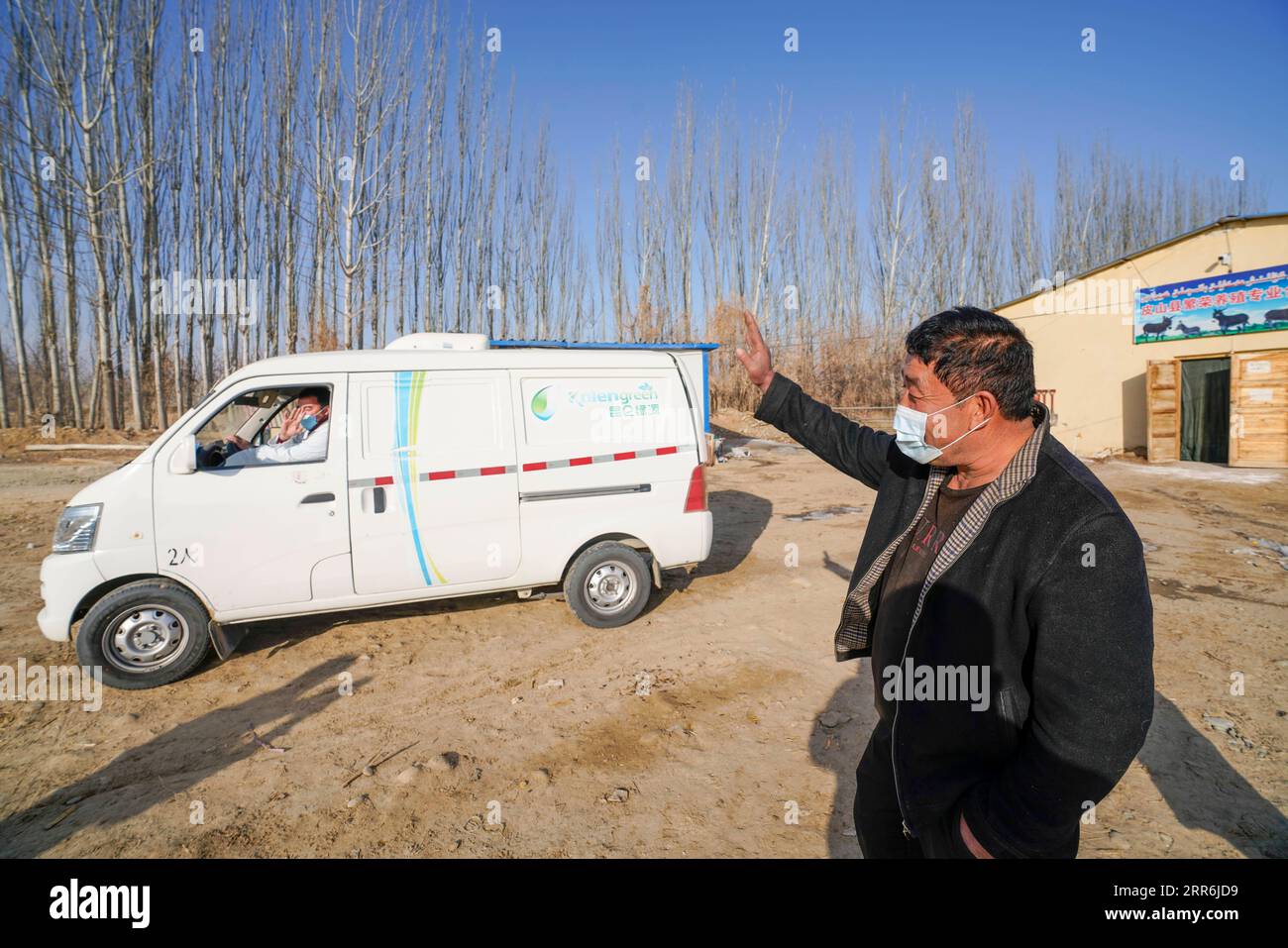 210218 -- HOTAN, Feb. 18, 2021 -- Ghulam Tuniyaz waves greetings to staff members of a local company coming to purchase donkey milk from his cooperative at Jiayi Nagute Village, Koxtag Township, Pishan County, in Hotan of northwest China s Xinjiang Uygur Autonomous Region, Feb. 4, 2021. Five years ago, Ghulam Tuniyaz, now officer in charge of a breeding cooperative at Jiayi Nagute Village, happened to lay his hands on a donkey entrusted with him by his son Memet Ghulam. Memet got this hairy thing for free as part of poverty alleviation efforts of the local authority, but decided to turn his ey Stock Photo