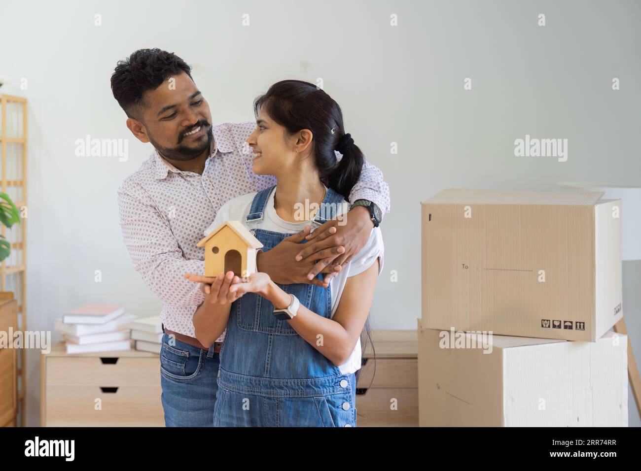 Married Indian couple owners holding house model moving in new home ...