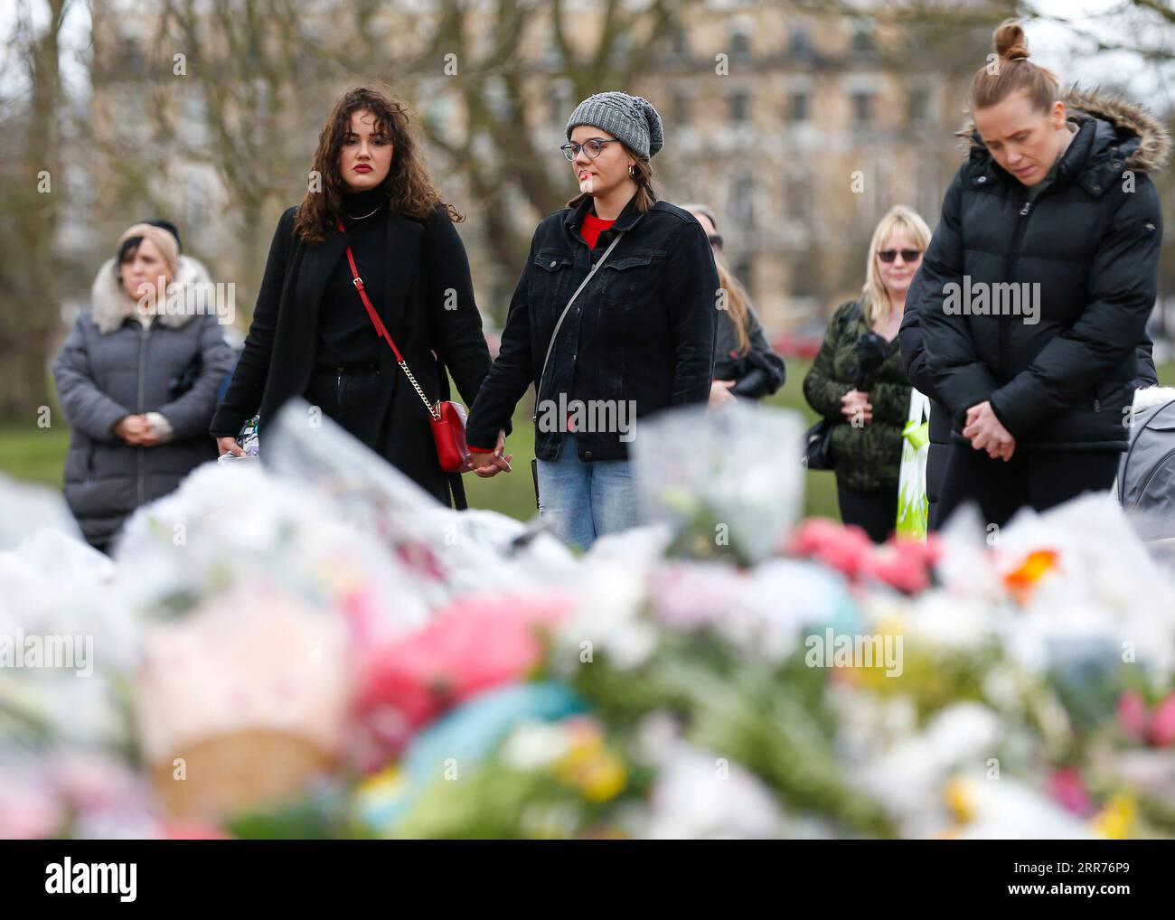 210316 -- LONDON, March 16, 2021 -- Women stand hand in hand next to floral tributes at the bandstand on Clapham Common to mourn for Sarah Everard in London, Britain, on March 15, 2021. A serving Metropolitan police officer on March 13 appeared in court in London after being charged with the kidnap and murder of a 33-year-old woman. Wayne Couzens, 48, was arrested after Sarah Everard, a marketing executive, went missing while walking home from a friend s apartment in south London on March 3. Everard s death has caused widespread concern in Britain about women s safety, with many women and girl Stock Photo