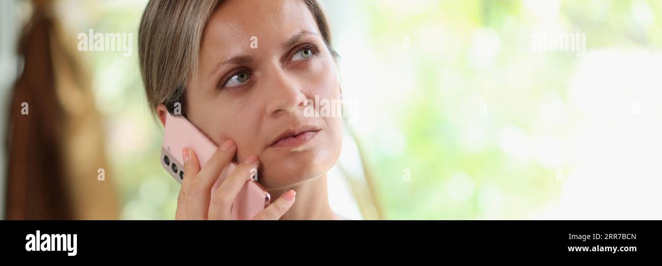 Thoughtful female speaking on smartphone at home Stock Photo