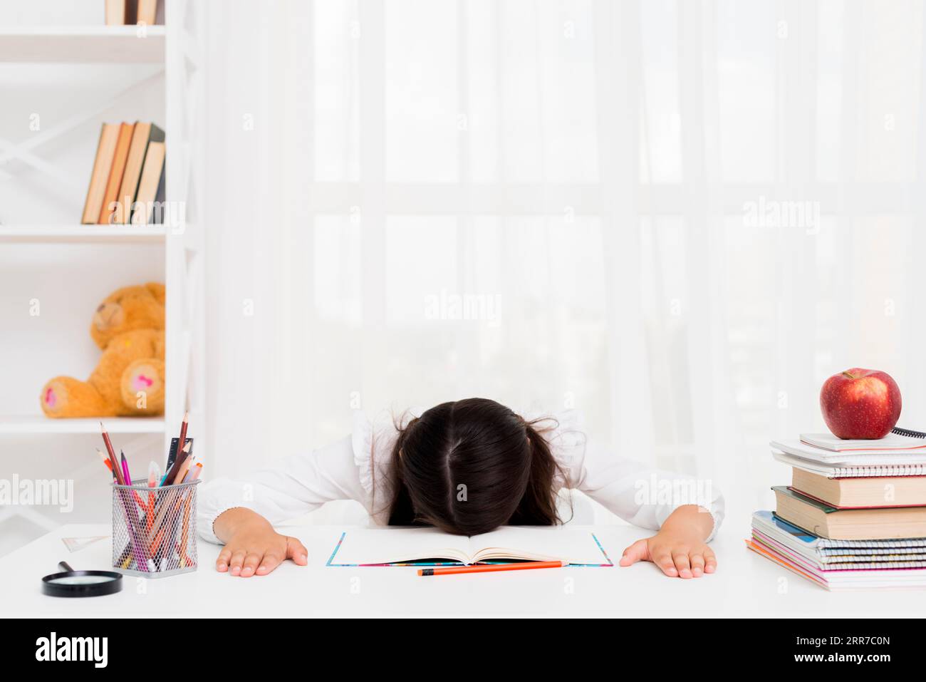 Tired schoolgirl lying copybook Stock Photo