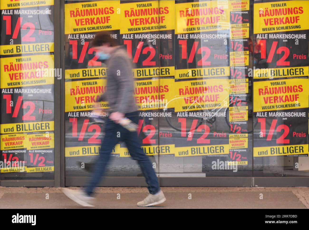 210326 -- BERLIN, March 26, 2021 -- A pedestrian wearing face mask walks past sale advertisements of a shop in Berlin, capital of Germany, March 25, 2021. Daily COVID-19 infections in Germany rose sharply as 22,657 new cases were registered within one day, about 5,100 more than one week ago, the Robert Koch Institute RKI said Thursday. The country s seven-day COVID-19 incidence rate also rose from 108.1 per 100,000 people in the previous day to 113.3 Thursday, according to the federal government agency for disease control and prevention. Photo by /Xinhua GERMANY-BERLIN-COVID-19-CASES StefanxZe Stock Photo