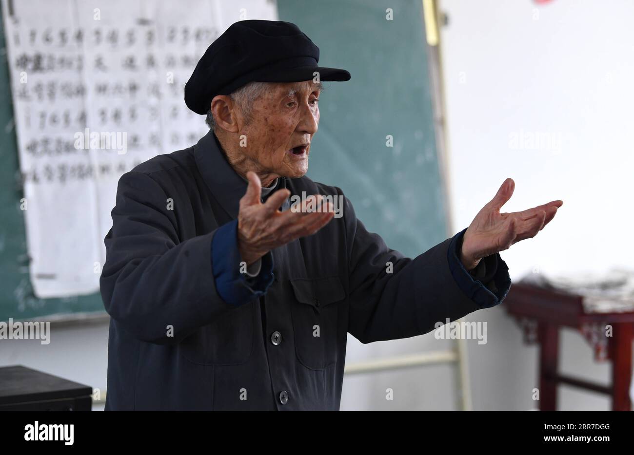 210326 -- HEFEI, March 26, 2021 -- Yan Mingyou teaches a song to students at Zhuwan Primary School in Zhuwan Township of Dingyuan County, Chuzhou City, east China s Anhui Province, March 23, 2021. Yan Mingyou, 92, is still at the post of teaching music at rural elementary schools. Retiring as a rural teacher in 1990, Yan has been volunteering to teach music to students in rural schools. Back to 1953, Yan left the army and returned to his hometown Zhuwan Township in Dingyuan County. He gave up a better job at local government and chose to work in rural schools, teaching various subjects like po Stock Photo