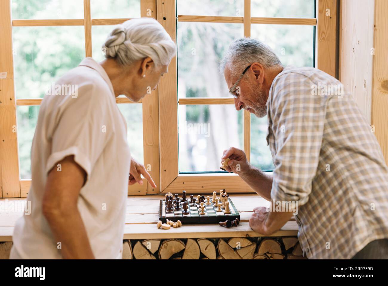 Senior couple playing chess window sill Stock Photo