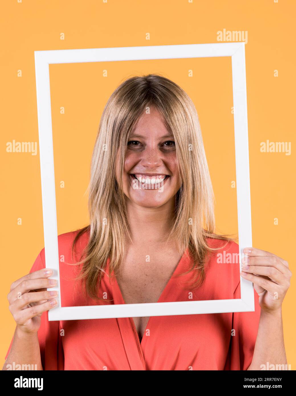 Young smiling woman holding white border frame front her face Stock Photo