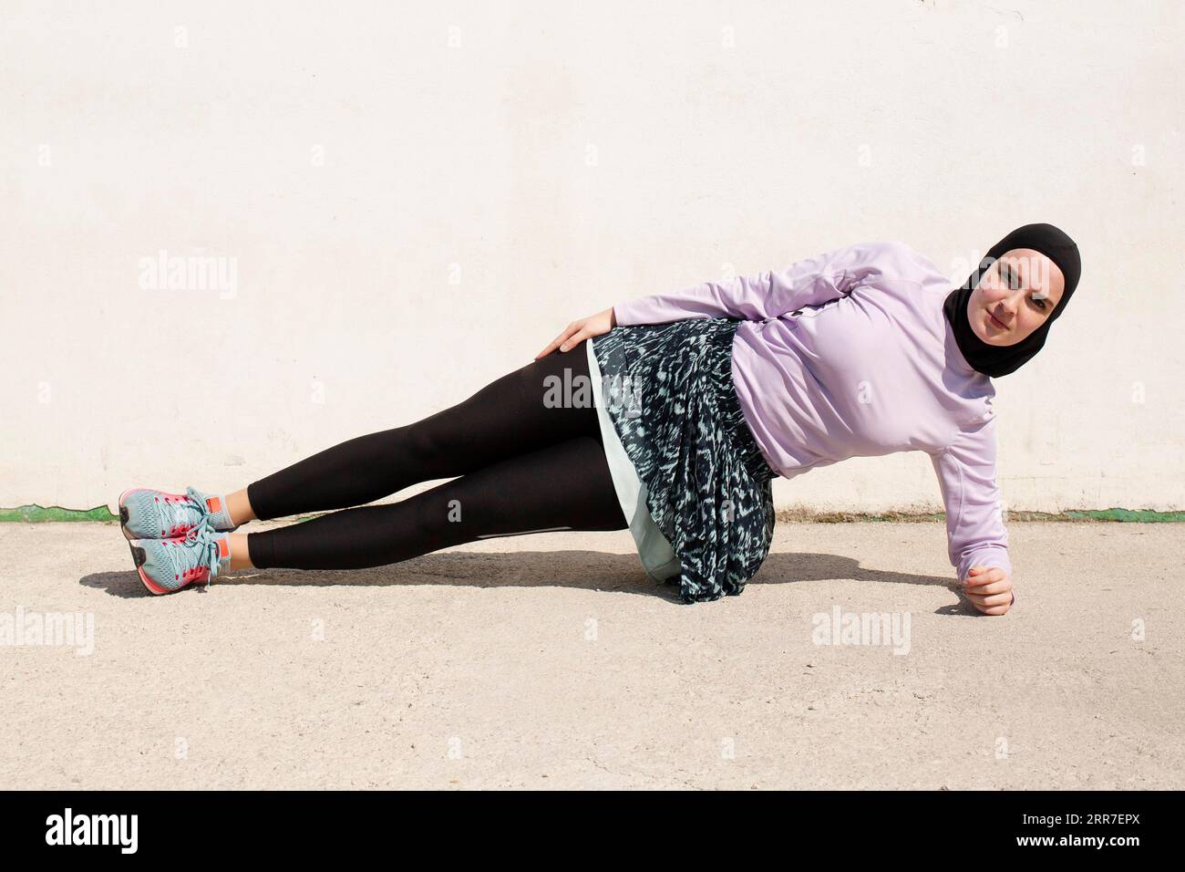 Woman with purple jacket doing side planks Stock Photo