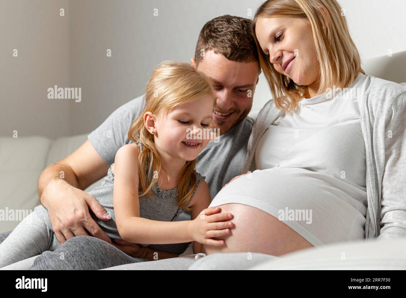 Beautiful little girl touching mother belly Stock Photo