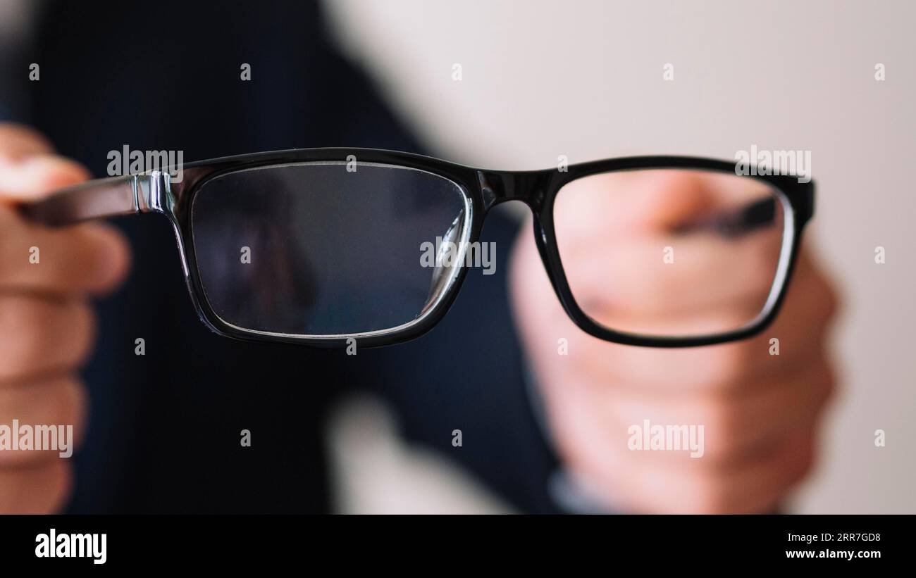 Man holding pair glasses with black frame Stock Photo