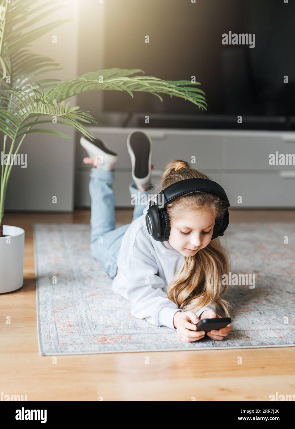 Smiling little girl listening music lying on the floor Stock Photo - Alamy