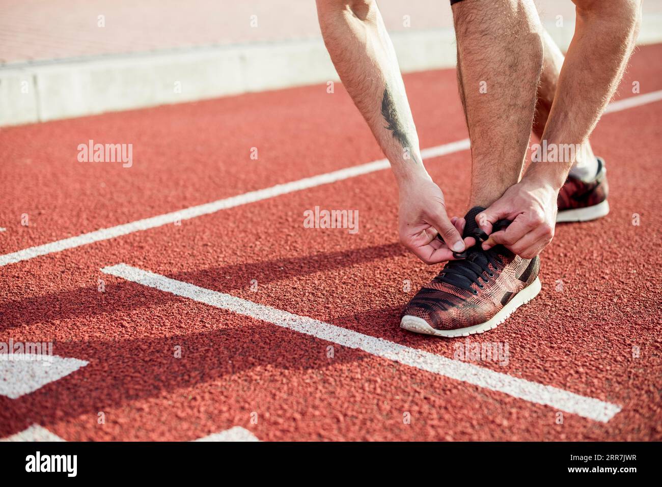 Low section male athlete start line tying his shoelace running track